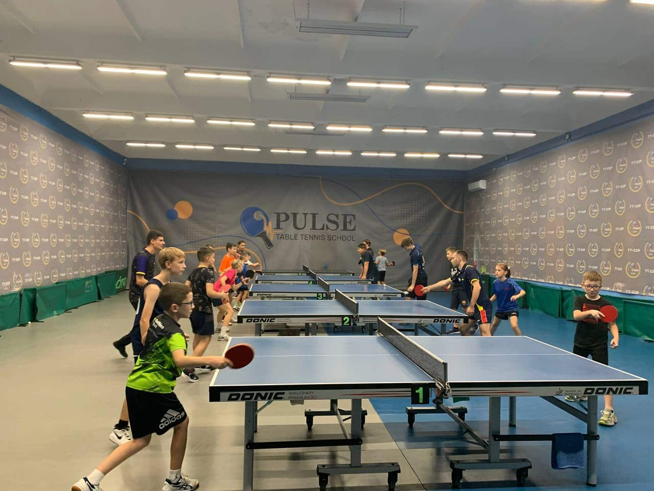 Children playing table tennis inside a room.