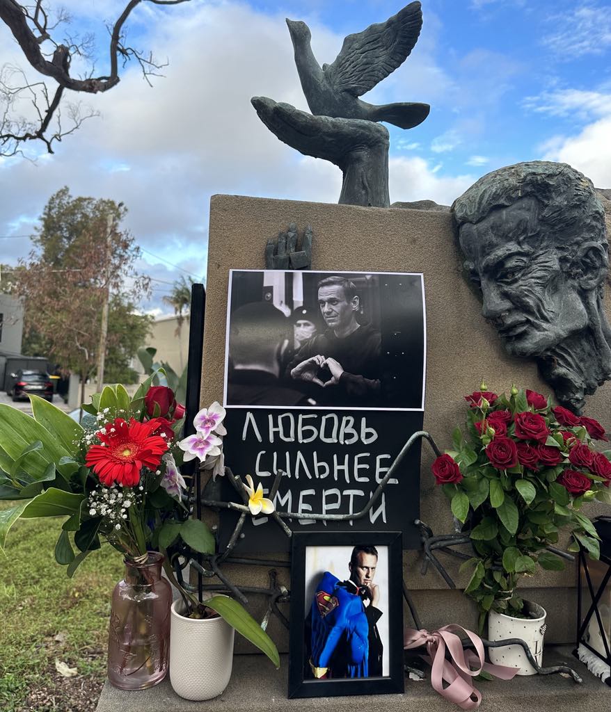 A memorial with a sculpture and flowers laid at the bottom