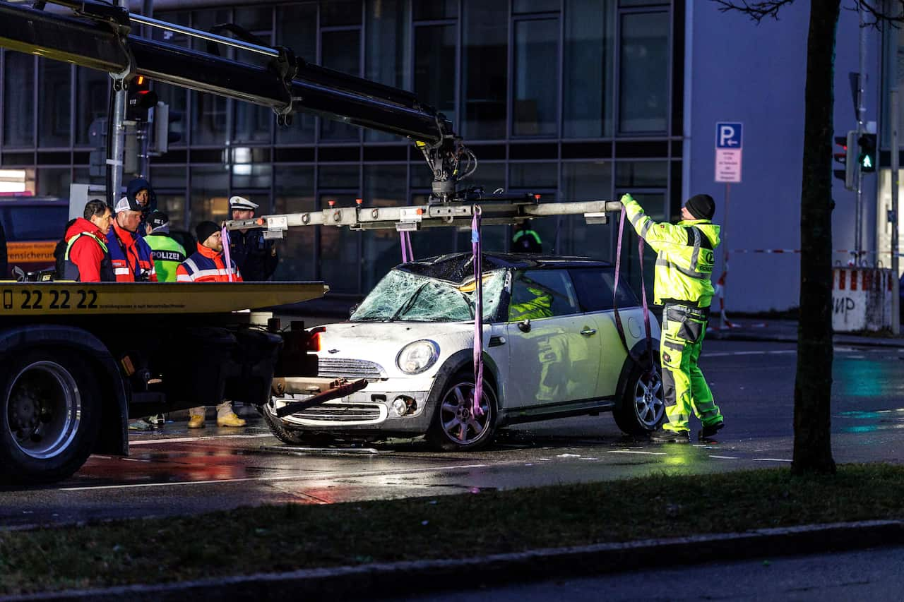 A white car is lifted onto a tow truck.