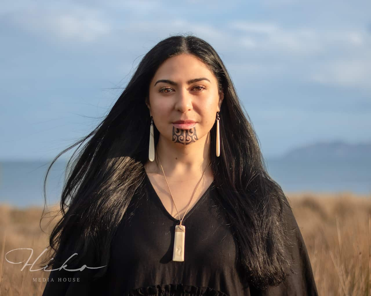 A woman with face tattoos wearing a black dress.