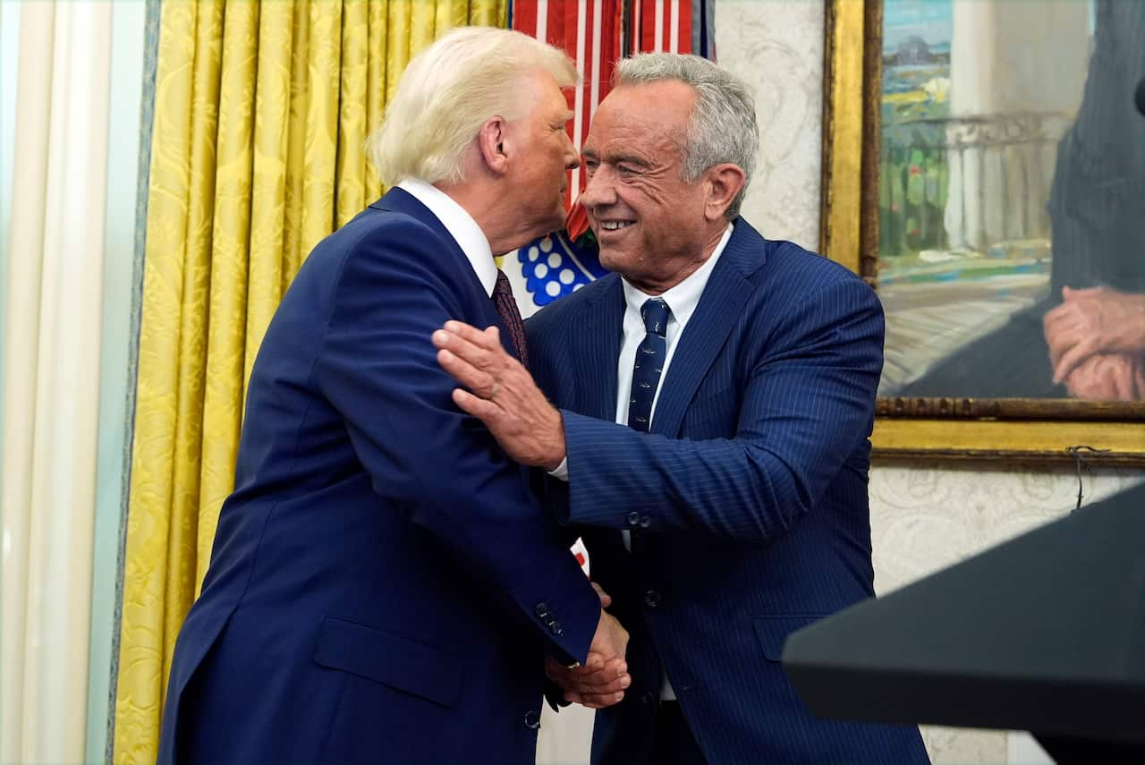 Two men in blue suits hug and shake hands.