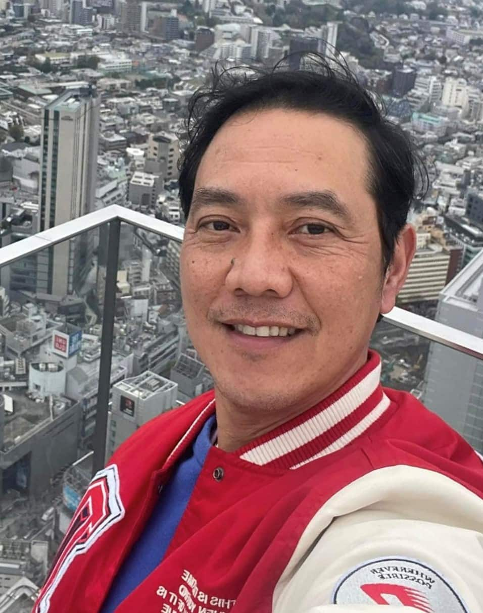 A man wearing a red jacket takes a selfie