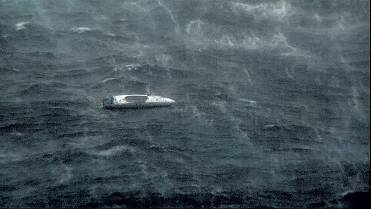 An ocean rowing boat in distress in a rough sea.